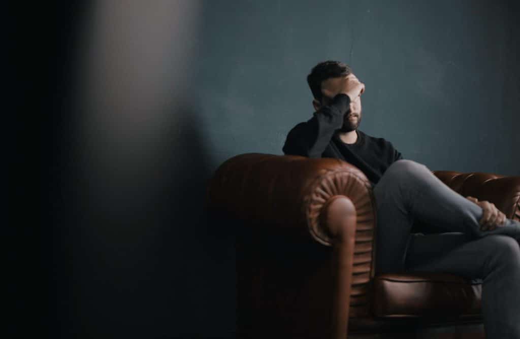 Man sitting on a couch with his face in his hands